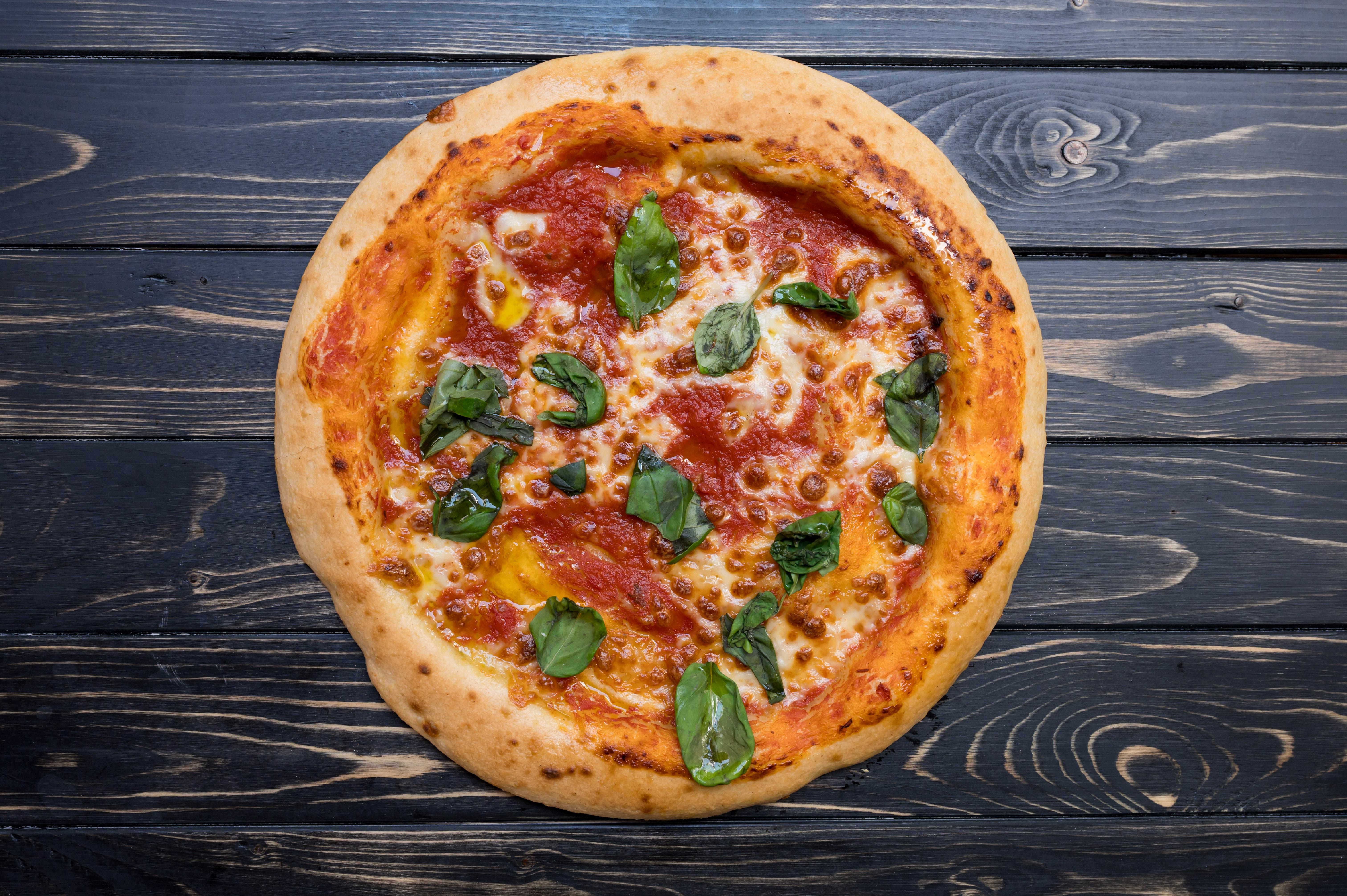Glutenfreie Pizza Margherita auf dunklem Holztisch
